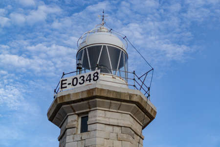 Upper part of the Punta Nati lighthouse in the north of Menorca, on a background of intense blue sky with white clouds forming altocumulusの写真素材
