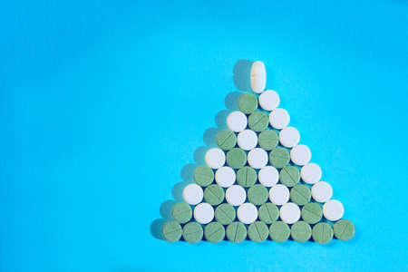 Christmas tree made of green and white pills over blue background. Holidays, Christmas, pills, medical concept. Abstract Christmas background.の写真素材