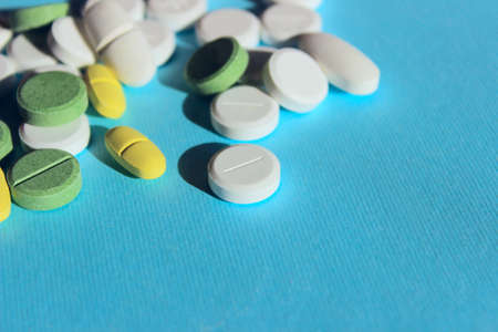 White, yellow and green peels scattered on blue background. Medical concept.