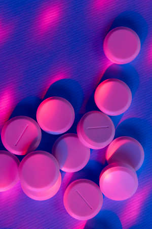 Pink pills over purple background. Pills, drugs, health and medicine concept. Abstract colorful...