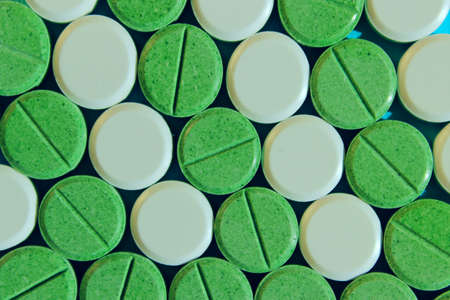 Green and white pills scattered on yellow background. Helth and medical concept. Colorful drugs...