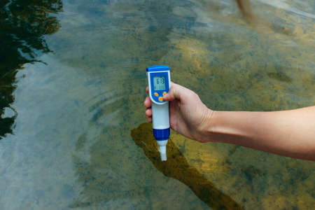 A woman's hand holds a waterproof tester pen and measures the total concentration of dissolved salts...