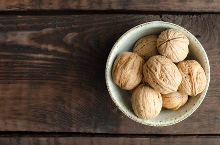 walnut with shell in bowl on wooden background. Top view with copyspaceの写真素材