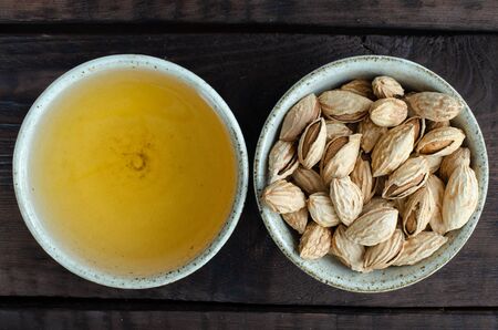 Green tea in cup and almonds in bowl on wooden backgroundの写真素材