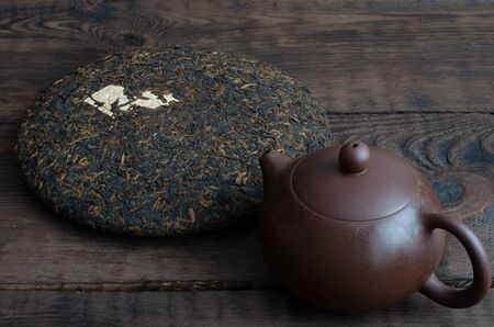 Chinese clay teapot and chinese black puerh on wooden background.の写真素材