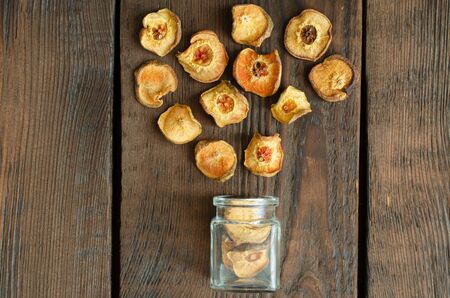 Dried pears from small glass bottle on wooden background. Top view.の写真素材