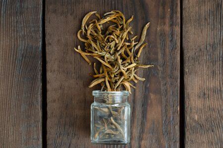 Golden buds. Chinese black tea from phial on wooden background. Top viewの写真素材