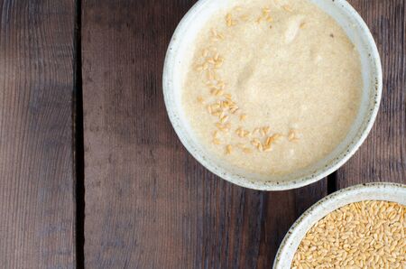 White linseeds in bowl and linseed porridge on wooden background with copy space. Top viewの写真素材