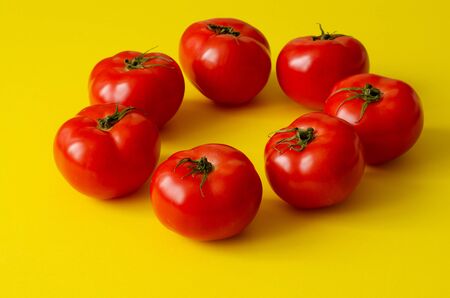 Circle of delicious tomatoes on yellow backgroundの写真素材
