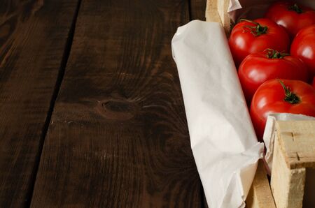 Delicious tomatoes in crate on wooden background with copy space.の写真素材