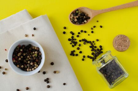 Different spices on yellow background. Black pepper in small phial. Red pepper, allspiceの写真素材