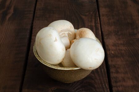 common meadow mushrooms in bowl on wooden backgroundの写真素材