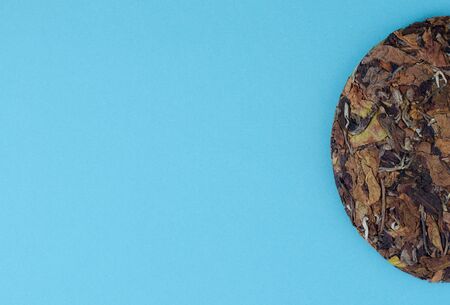 Pressed chinese white tea on blue background with copy space