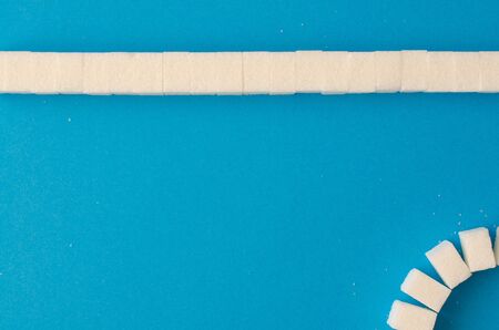 lump sugar line on blue background with copy space. Top viewの写真素材