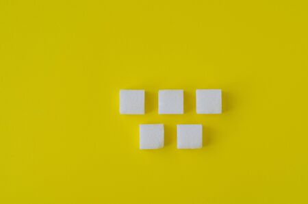 lump sugar cubes on yellow background. Abstract pattern. Chessboard pattern. Top viewの写真素材