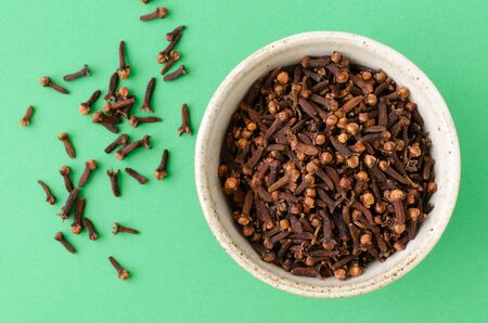 Cloves spice in bowl on green background. Top view.の写真素材