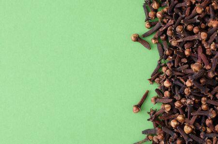 Cloves on light green background with copy space. Top view.