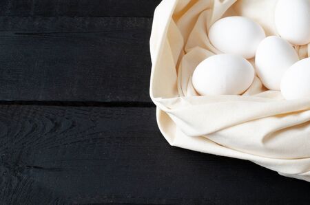 Chicken eggs on white linen on black background with copy space