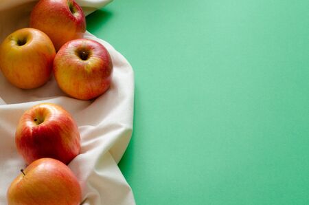 Organic apples on white linen on green background with copyspaceの写真素材