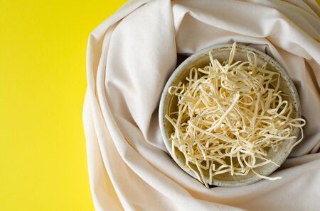 Noodles in clay bowl and linen on yellow background with copy space. Top viewの写真素材