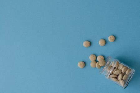 Herbal pills from small glass bottle on blueの写真素材