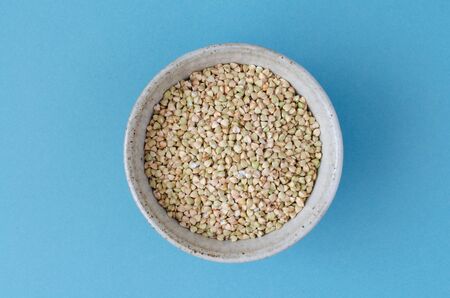 Green buckwheat in clay bowl on blueの写真素材