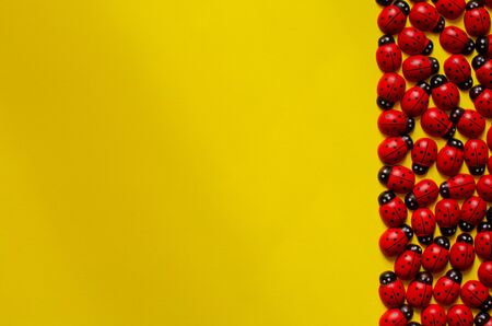 decorative wooden ladybugs on yellow background with copy space. Ladybug pattern. Top view.の写真素材