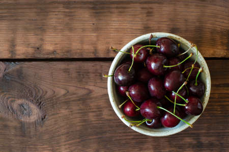 Sweet cherry in bowl on wooden background. Top view.の写真素材