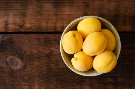 apricots in bowl on wooden background.の写真素材