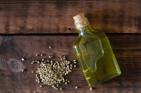 Bottle of hemp oil and hemp seeds on wooden background. Top view.の写真素材