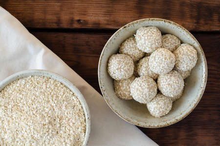 sesame seed balls and sesame squeezed seeds in bowls on linen and wooden background. Top view.の写真素材
