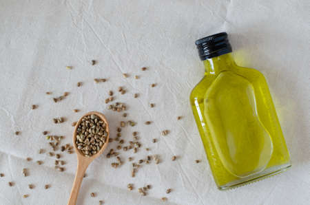 bottle of hempseed oil and wooden spoon with hemp seeds on linen background. Top viewの写真素材