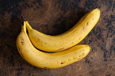 two yellow bananas on abstract wooden backdrop. Top viewの写真素材