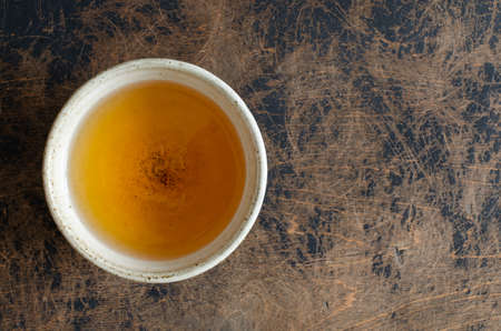 green puer tea in clay cup on abstract wooden backdrop.の写真素材