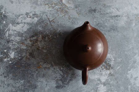 clay teapot on abstract gray painted wooden backdrop.の写真素材