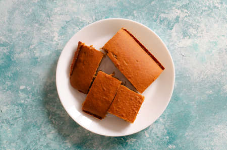 pieces of sponge cake on white plate on abstract aqua background. Beautiful texture. Top view.