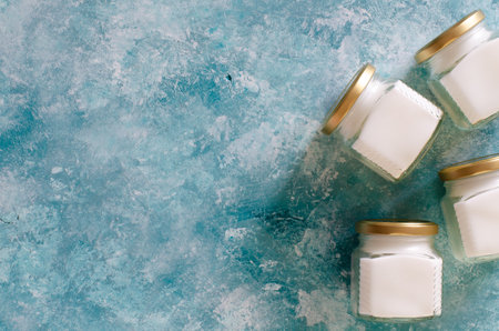 Raw virgin coconut oil in glass jars on abstract aqua blue background with copy space. Top view.の写真素材