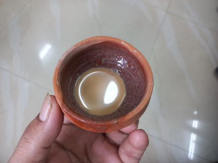 This photo shows a traditional kulhad (clay cup) filled with chai (Indian tea). These clay cups are commonly used to serve hot tea in India, especially at roadside tea shops.の写真素材
