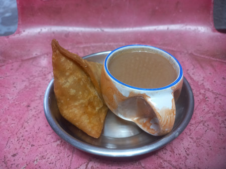 A small steel plate with one potato samosa and a cup of teaの写真素材