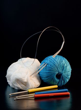 colorful yarn balls with needles and knitting hooks over blackの写真素材