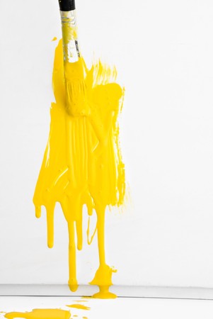 Painting the wall with yellow paint and old used brushの写真素材