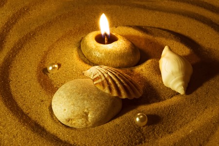 Summer evening background. Candle, seashells, stone and pearls on sand. Gold tinted imageの写真素材