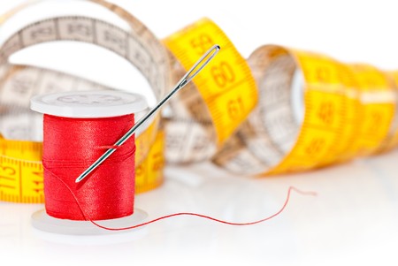 Colored bobbin for sewing and measuring tape over whiteの写真素材