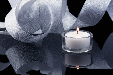 Decoration with burning candle and shining ribbon on black. Blue tinted imageの写真素材