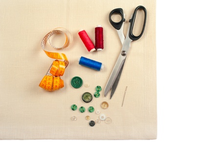 Sewing supplies. Set from measuring tape, buttons, bobbins of thread, needle and scissors on linen...