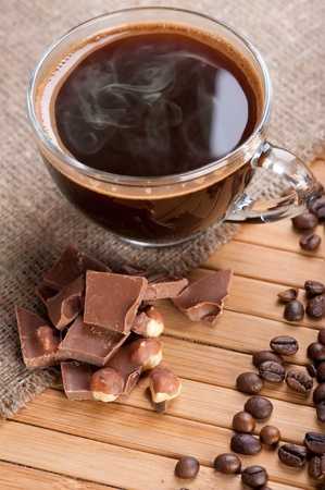 Cup of coffee, chocolate with nuts and coffee beans on wooden background with linen canvasの写真素材