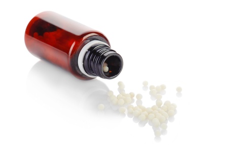 Herbal remedy alternative medicine. Bottle and globule of homeopathic medication on white backgroundの写真素材