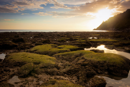 Ocean landscape of tropical beach with rocks and stones under colorful dramatic sunset sky. Cay at evening low tide. Thailand, Phuketの写真素材