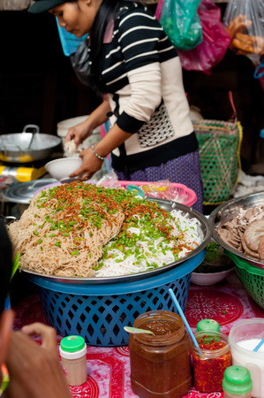 SIEM REAP, CAMBODIA - DEC 22, 2013: Unidentified Khmer woman selling noodles at traditional food marketplace on Dec 22, 2013 in Siem Reap, Cambodia. Street food markets is popular tradition in asiaのeditorial素材