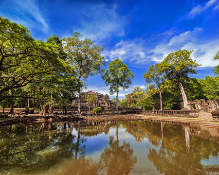 Ancient Khmer architecture. Outdoor park landscape with lake and panorama view of Baphuon temple ruins at Angkor Wat complex, Siem Reap, Cambodiaの写真素材